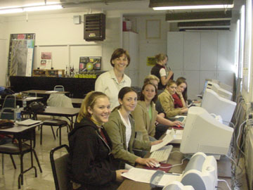 Students posing for the camera in front of their computers.